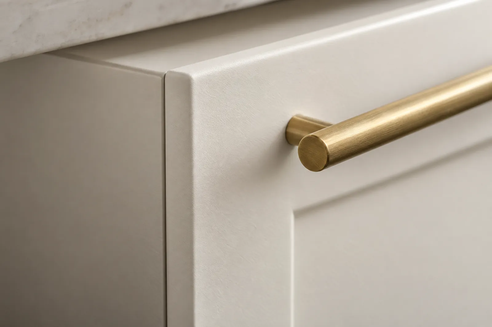 Close-up of a seamlessly wrapped cabinet door corner in satin warm white with a brass pull