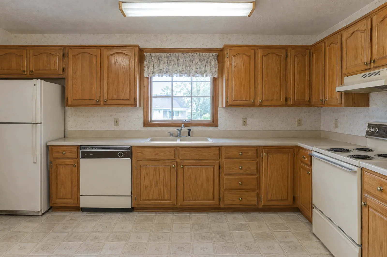 Dated kitchen with honey oak cabinets and almond appliances before wrapping
